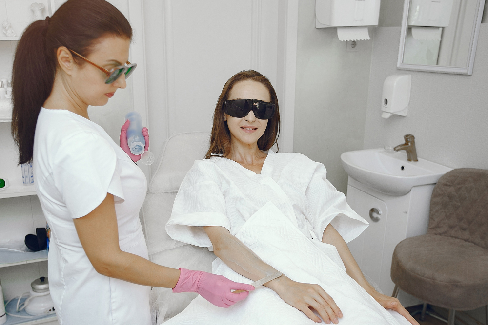 A woman in a hospital gown enjoys a hair styling session at Day Dreams Med Spa in Omaha, focusing on laser hair removal.